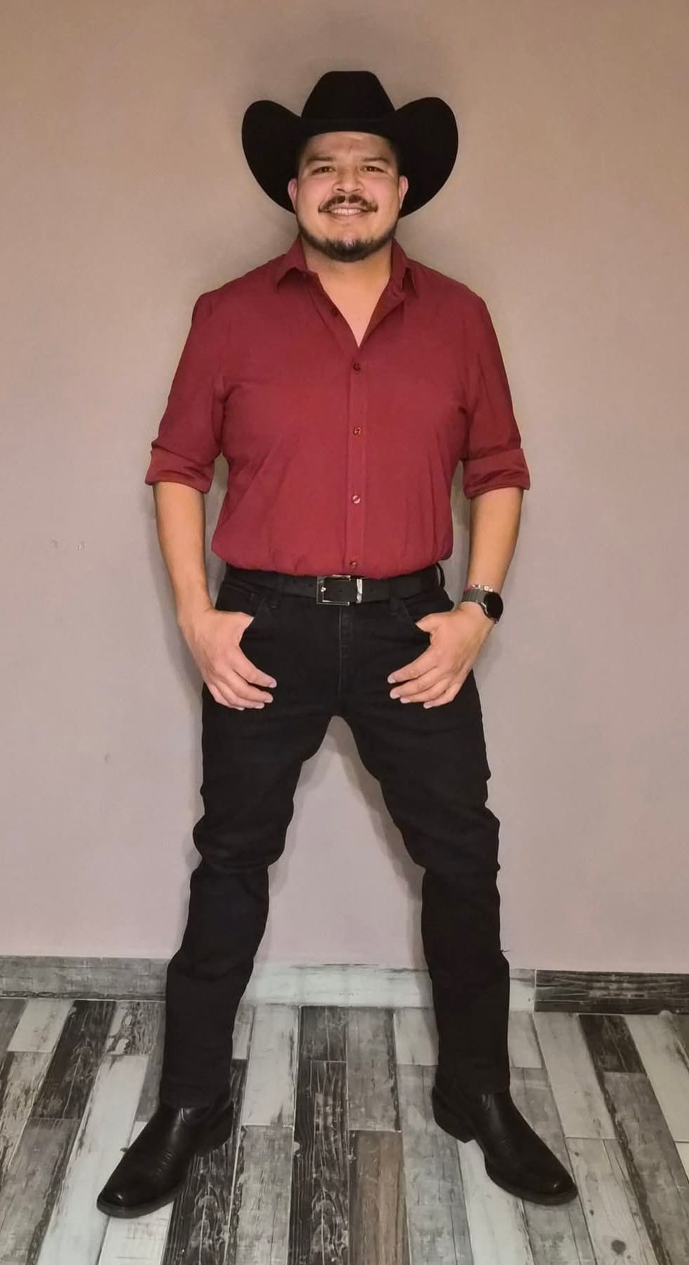 The founder today, wearing a red button-down shirt, black pants and black cowboy hat